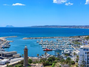 A marina with boats, a lighthouse, and a coastal town.