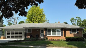 A single-story house with a garage, a front porch, and a brick facade. - 3-bedroom house in charming Green Bay, walking distance to LAMBEAU!! (Green Bay)