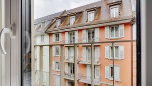 A multi-story building with balconies and windows, viewed through a window with a metal frame. - Blueground | Wiedikon, AC & w/d, nr museums (Zurich)