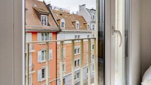 A balcony with a view of adjacent buildings, a metal railing, and a door.