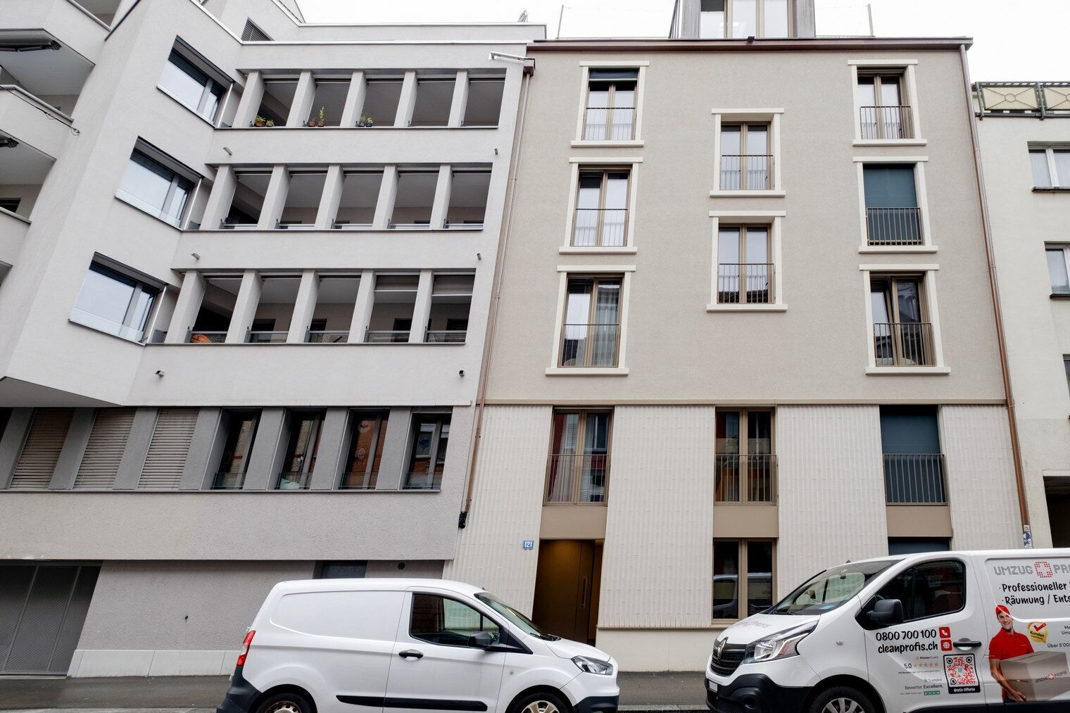 Ein mehrstöckiges Gebäude mit einer glatten Fassade, großen Fenstern und einer Tür mit einem Metallgitter.