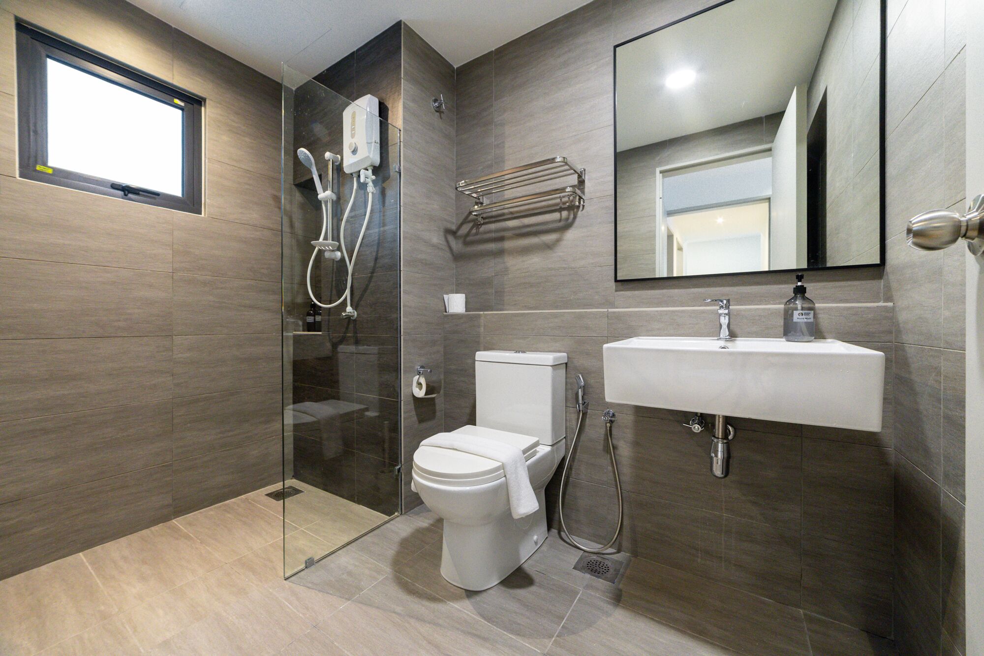 A modern bathroom with a glass-enclosed shower, a toilet, a sink, and a mirror.