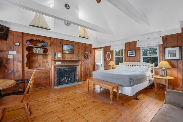 A cozy room with wooden walls, a fireplace, a bed, and a dining area.