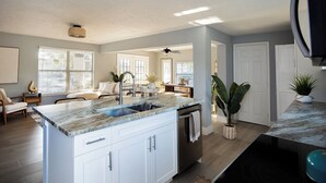 A modern kitchen with white cabinetry, a marble countertop, and a built-in dishwasher. - Charming 3-bedroom villa with AC, WiFi in tranquil Naples (Naples)