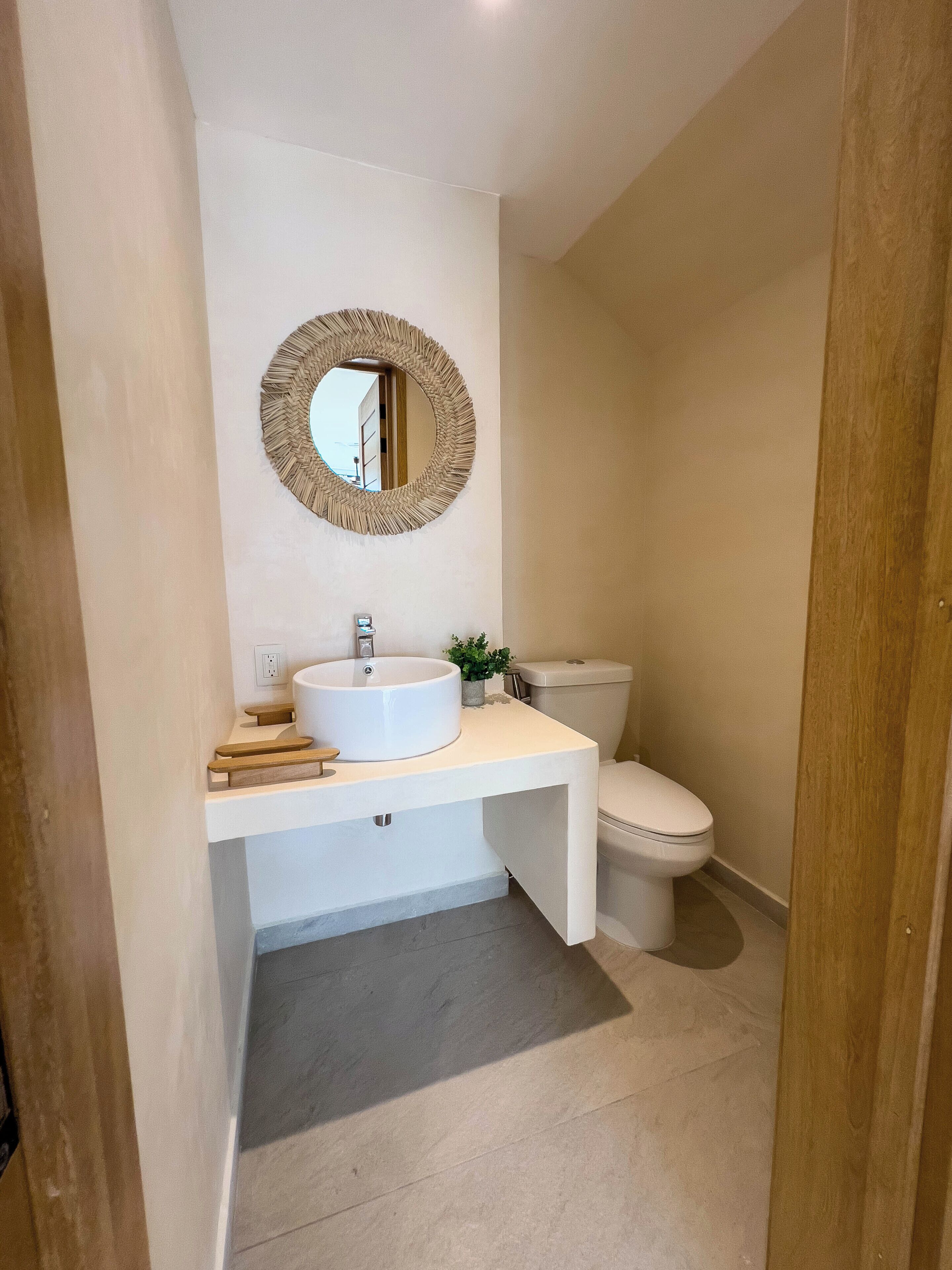 A bathroom with a white sink, a round mirror, and a toilet.