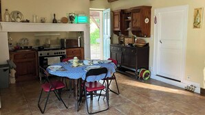 Una cocina con una mesa de comedor para cuatro personas, armarios de madera, una estufa y un microondas.