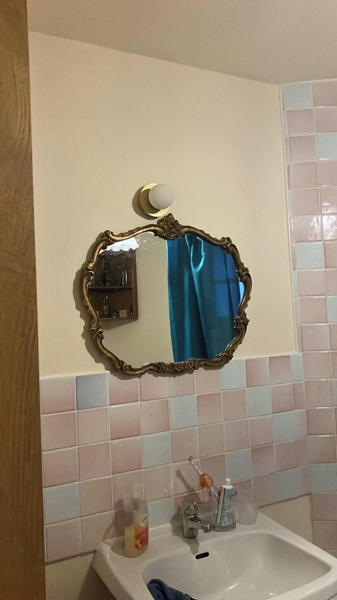 Een badkamer met een spiegel, wastafel en betegelde wanden.