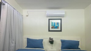 A room with two beds, a nightstand, a framed picture, and an air conditioning unit. - Twin Patio Hideaway (Nassau)