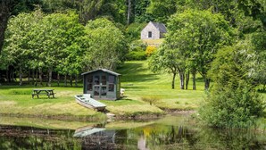 A lakeside cabin with a dock, a picnic table, and a small shed.