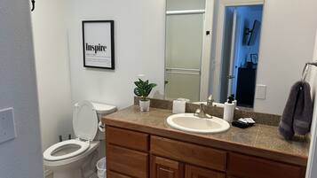 A bathroom with a toilet, sink, vanity, and a mirror.