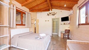 A bedroom with a bed, a desk, a chair, a television, and a wooden ceiling. - Piccola Fattoria, Massa Marittima, Italy (Massa Marittima)