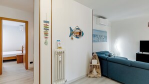 Een moderne woonkamer met een modulaire bank, een radiator, een visdecoratie aan de muur en een ingelijst stadsbeeld.