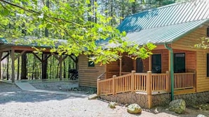 Eine Holzhütte mit Veranda, umgeben von Bäumen.