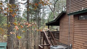 Eine Holzhütte mit einer Holzterrasse und Treppen zu einem überdachten Bereich.