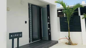 Un bâtiment moderne à l’extérieur blanc, avec une porte noire et une petite enseigne devant.