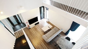 Un appartement moderne doté d’un espace de vie comprenant un téléviseur à écran plat, un canapé et une table à manger.