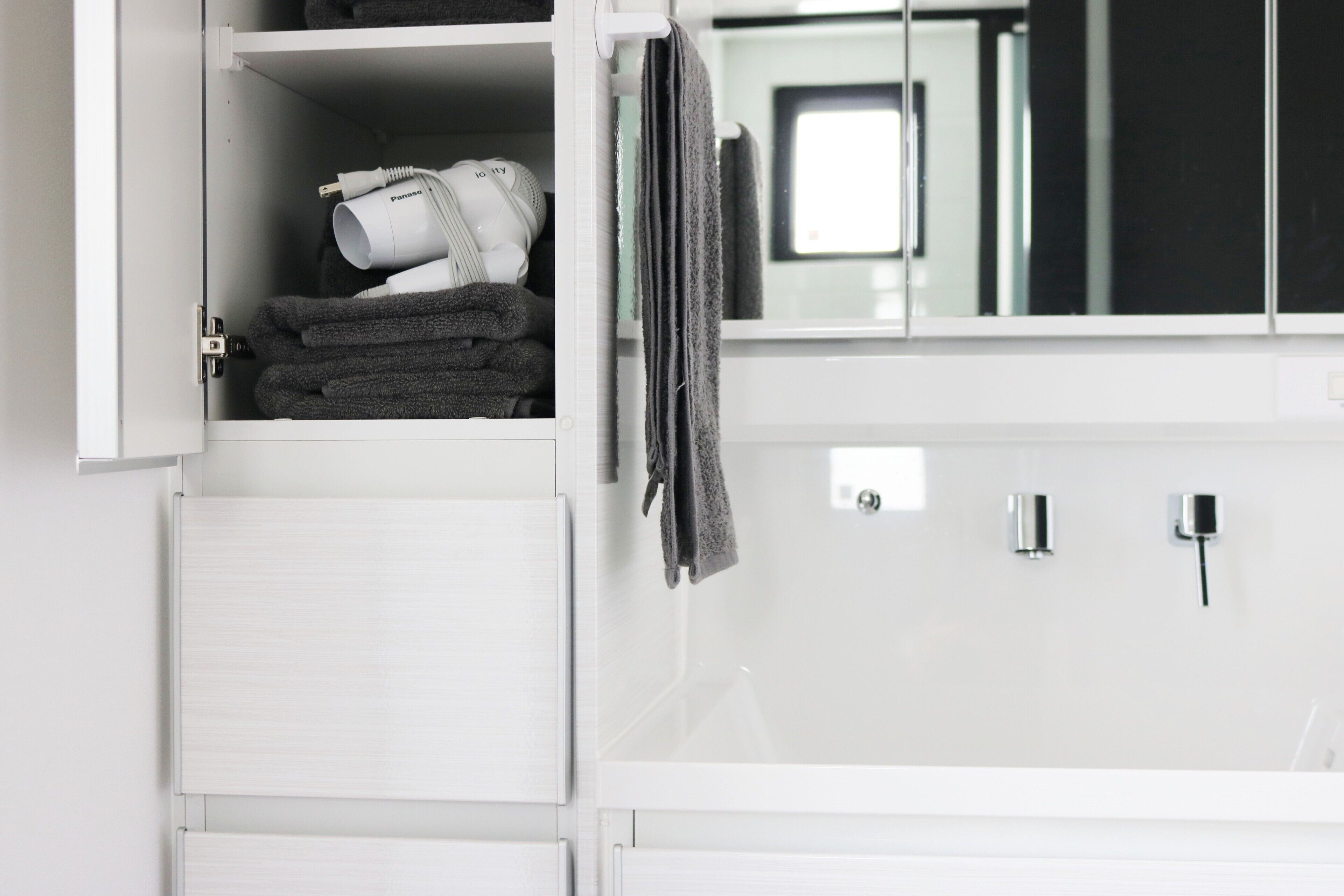 A bathroom with a white cabinet, a towel rack, and a mirror.