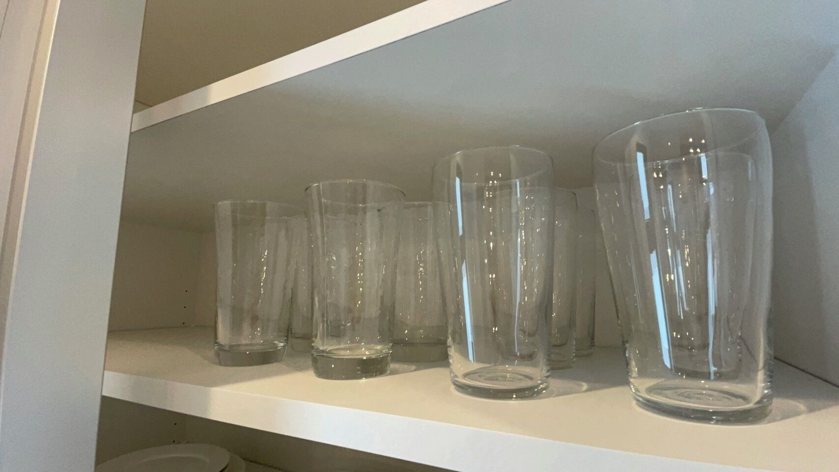 Une étagère avec plusieurs verres en verre transparent.