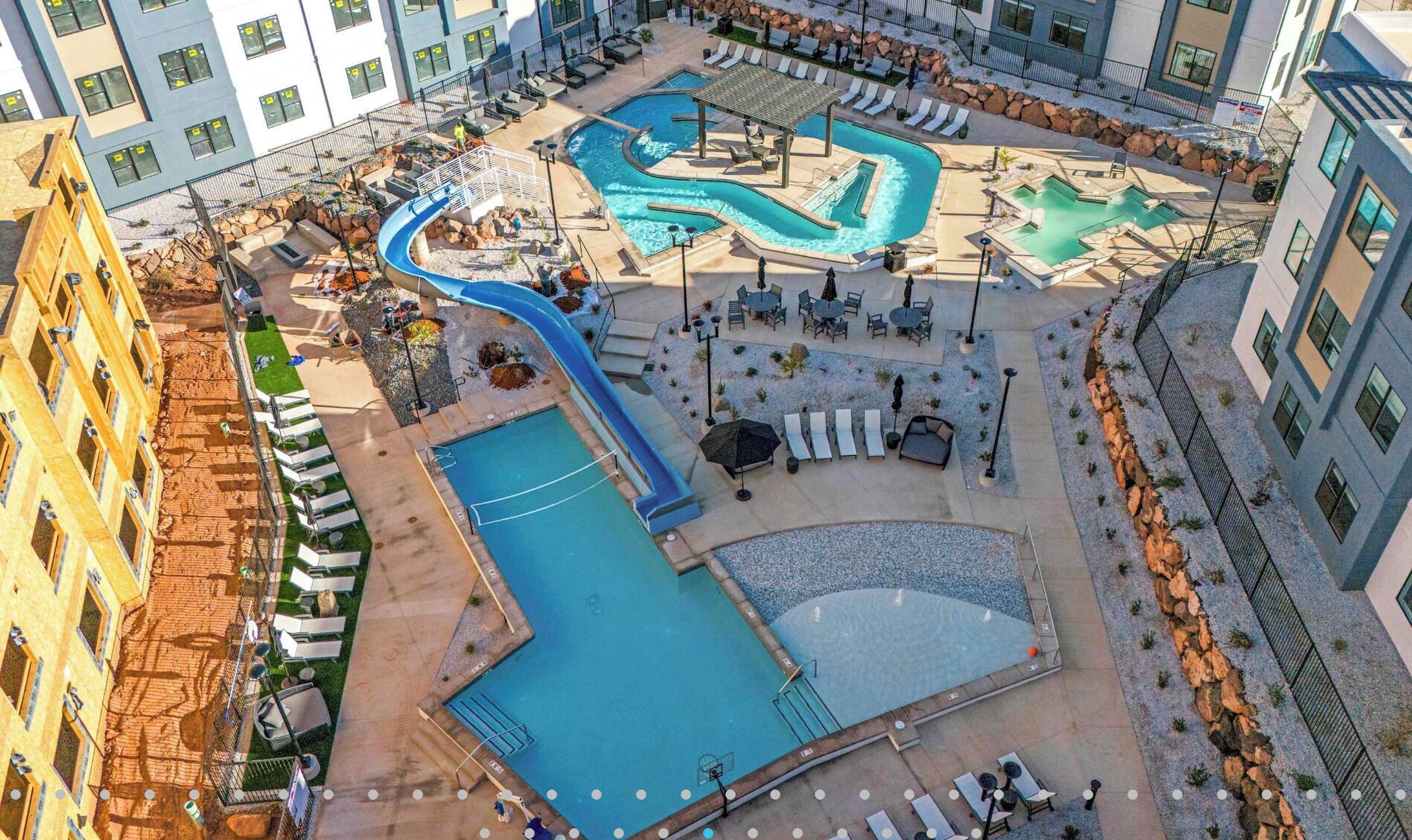 Un espace piscine sur le toit, comprenant plusieurs piscines, des chaises longues et un toboggan.