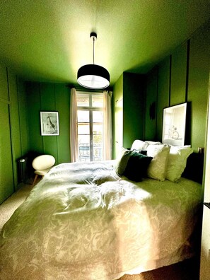 Relax in this serene bedroom with a large bed, a comfortable chair, and a beautiful view from the window.