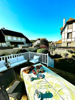Relax in a charming European-style courtyard with a wooden deck, complete with a bench, chair, and table set for a meal.