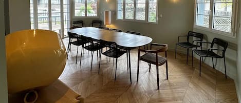 Un comedor amplio con una gran mesa ovalada, varias sillas y un piso de parqué de roble.