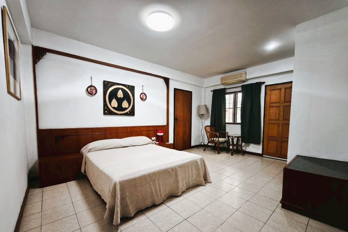 Ein Schlafzimmer mit Bett, Stuhl, Schreibtisch und Kleiderschrank.