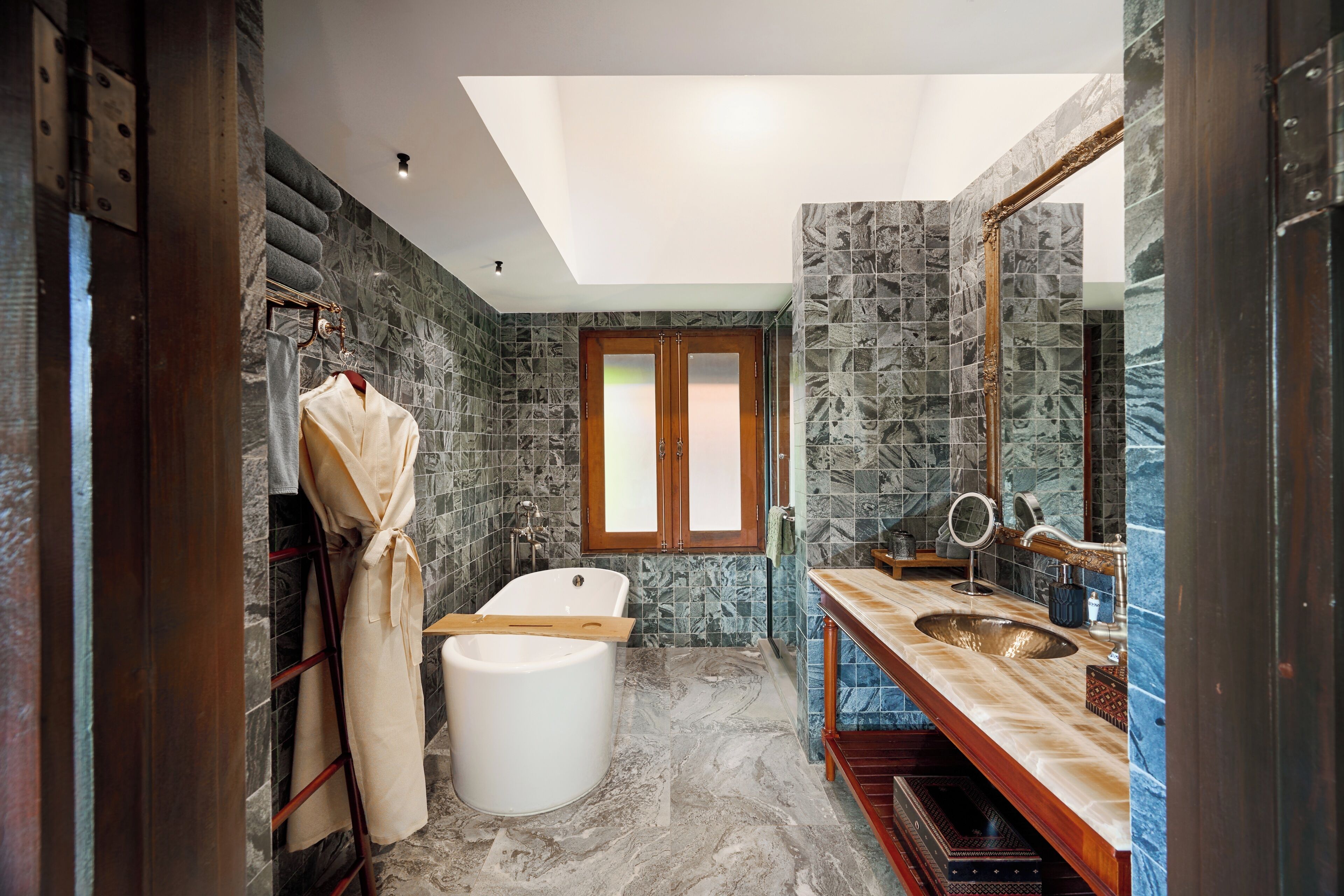 A modern bathroom with a bathtub, a wooden vanity, and a large mirror.