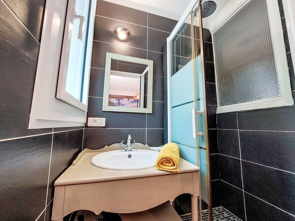 A bathroom with a sink, mirror, and shower.