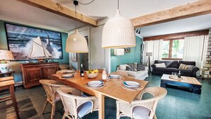 Un comedor con una mesa de madera, sillas de mimbre y lámparas colgantes.