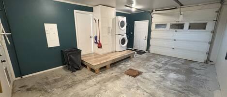 A garage with a concrete floor, a washing machine, a dryer, and a wooden bench.