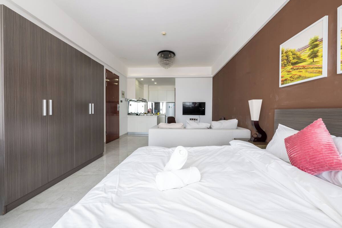 Una habitación de hotel moderna con una cama grande, un armario, un sofá y una televisión.