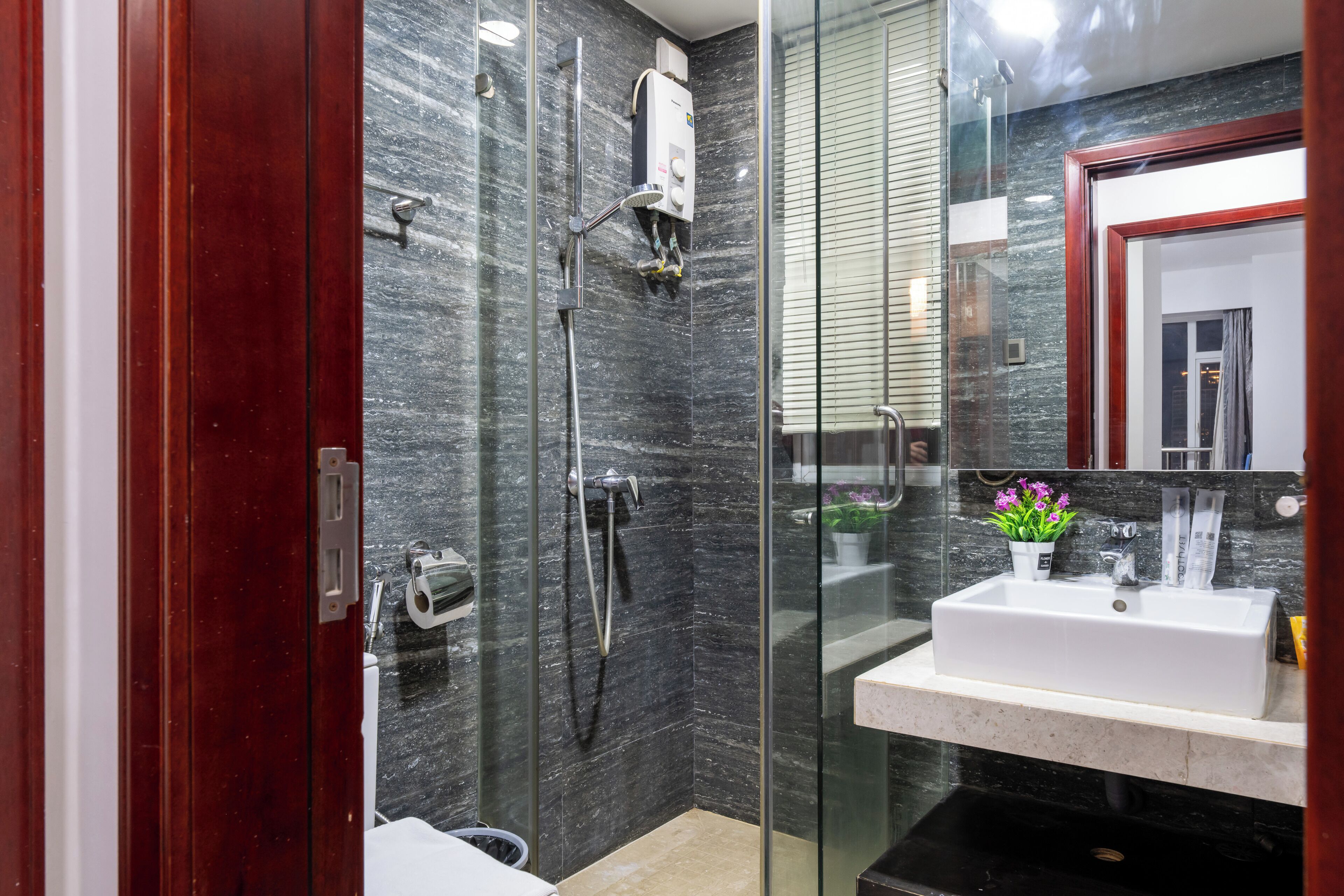 Un baño moderno con cabina de ducha de vidrio, un lavamanos blanco y un salpicadero de mármol.