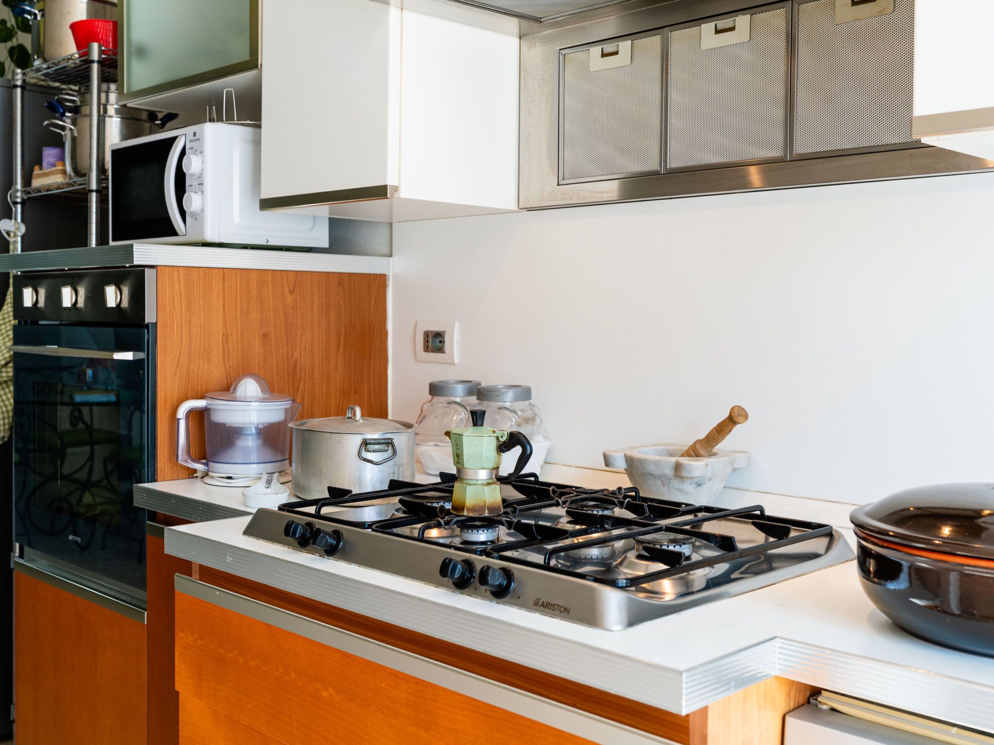 A kitchen with a stove, oven, microwave, and various kitchen utensils.