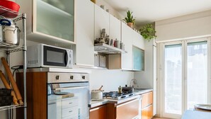 A modern kitchen with a built-in oven, microwave, and gas stove. There is a window providing natural light and a view of the outside.