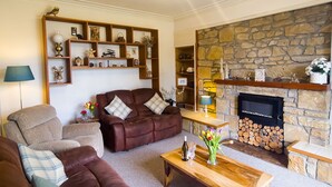 A cozy living room with a stone fireplace, a wooden bookshelf, and a comfortable seating area.