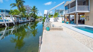 A waterfront property with a pool, a dock, and a covered outdoor seating area.