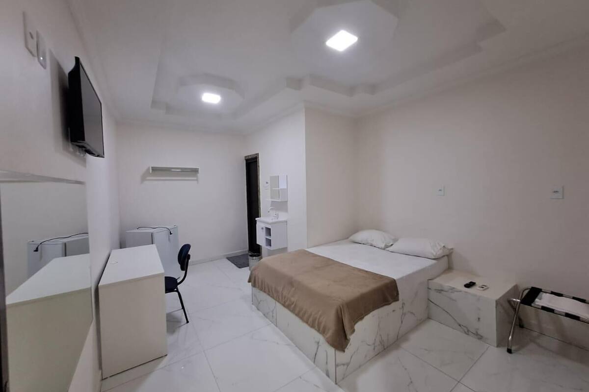 A modern bedroom with a bed, bedside table, and a desk with a chair.