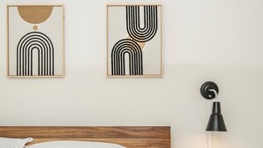 A neatly made bed with white and blue bedding, a wooden headboard, and two abstract wall art pieces. - Cozy Retro Gem for the Fam W/ AC (Near Roger&WEM) (Edmonton)