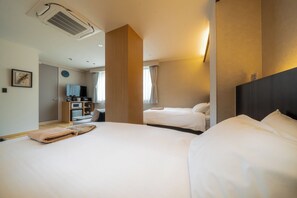 A hotel room with two beds, a television, a microwave, and a large window with curtains.