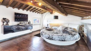 Une chambre avec un grand lit, une télévision et un plafond en bois.