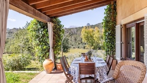 Un patio esterno con un tavolo rotondo, sedie e piante in vaso.