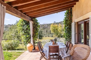 An outdoor patio with a round table, chairs, and potted plants.