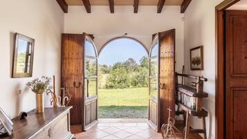 An open doorway leading to a garden with a bicycle and a bookshelf.
