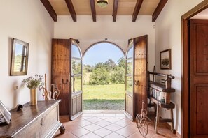 An open doorway leading to a garden with a bicycle and a bookshelf.