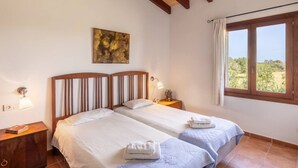 Una camera da letto con due letti, una finestra con tende, un quadro appeso al muro e una lampada da comodino.
