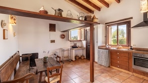 Una cucina rustica con travi in legno, un'area pranzo con una panca e una finestra che offre luce naturale.