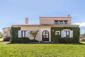A two-story house with a flat roof, a central entrance with a door, and shutters on the windows.