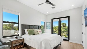 Un dormitorio con cama, mesita de noche, silla y ventilador de techo.