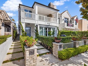 A two-story house with a balcony, a front porch, and a driveway leading to the entrance.